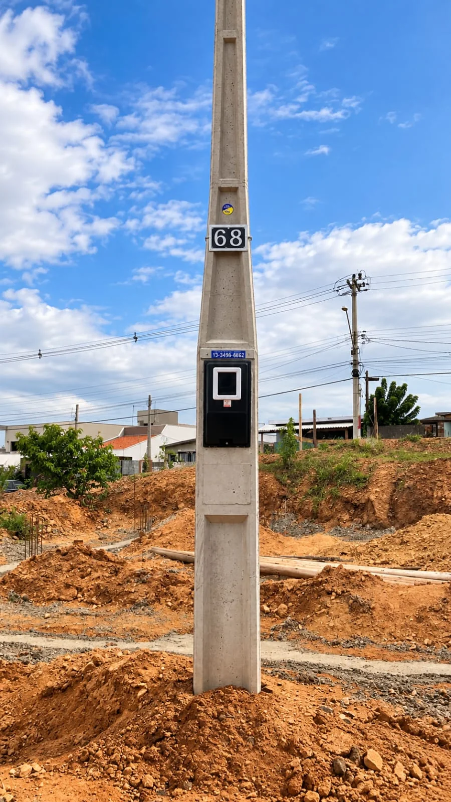 Poste bifásico com uma caixa preta de medição em terreno em obras